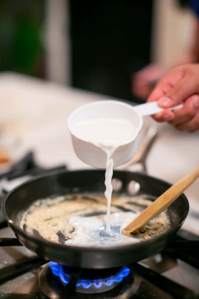 Pouring a cup of cream into a rue in the pan