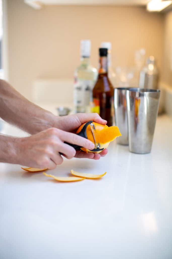 Man peeling an orange on top of a white counter