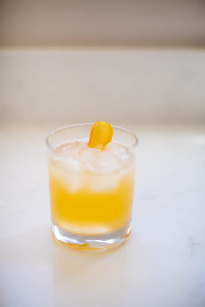 A cold mai tai cocktail in a clear small glass on a white surface