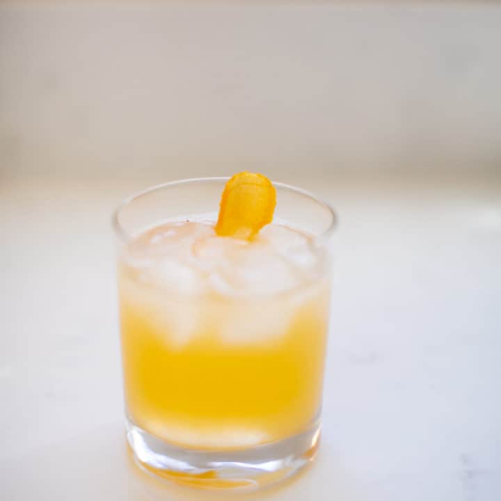 A cold mai tai cocktail in a clear small glass on a white surface
