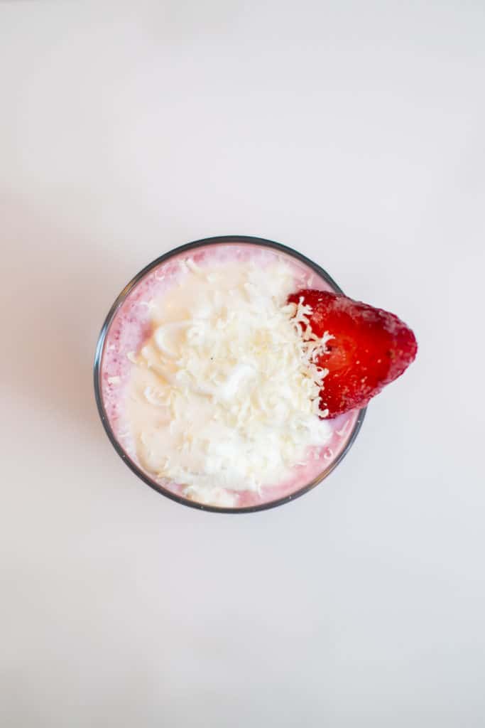 Top view of a strawberry milkshake with whipped cream and a strawberry