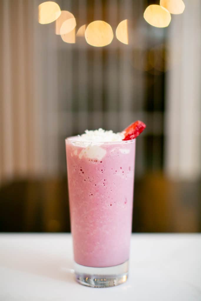 Glass of strawberry milkshake with whipped cream and a strawberry slice