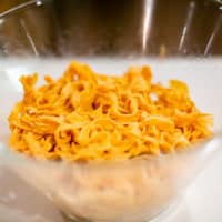 Red pepper pasta dough in a clear bowl placed on a white surface in the kitchen