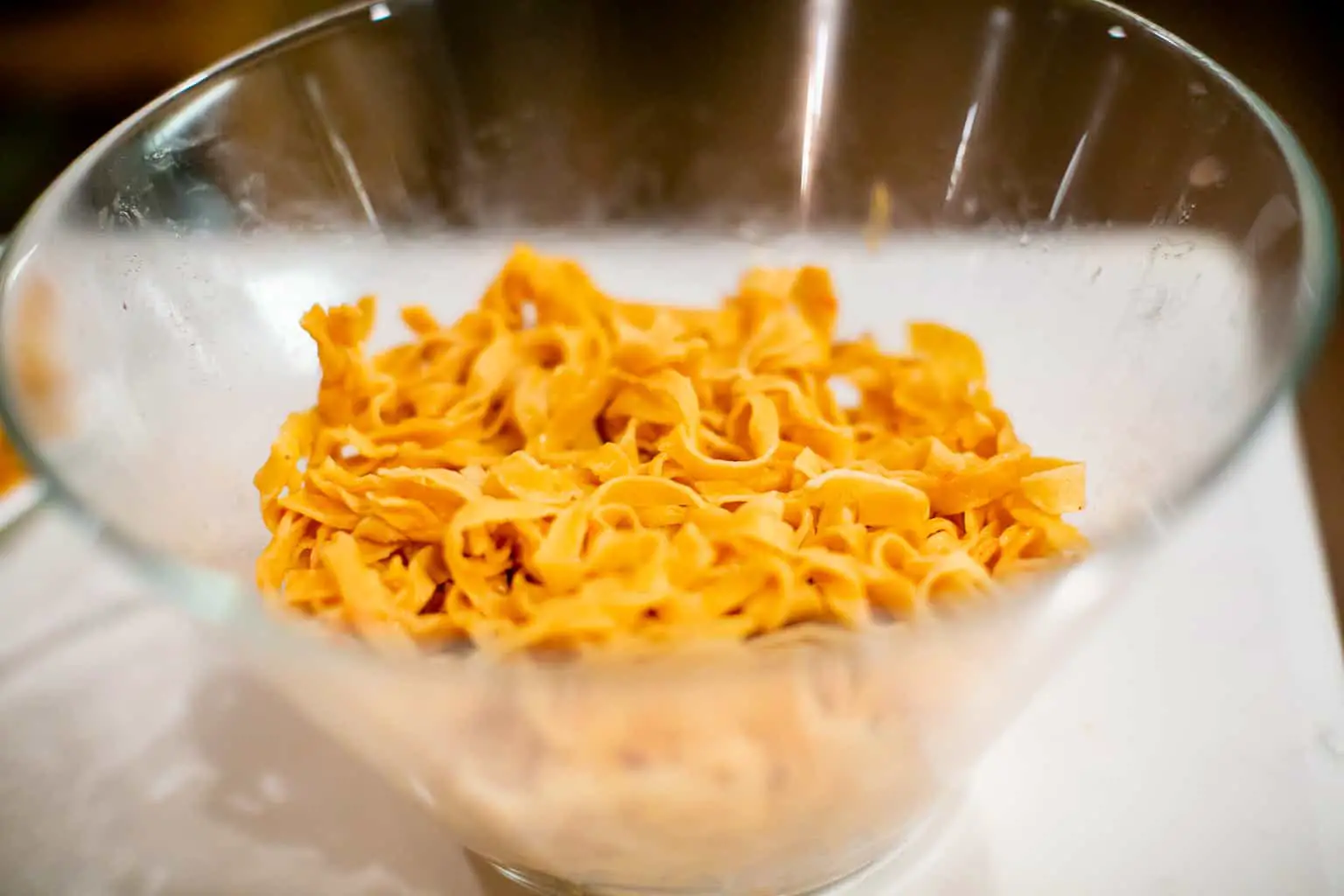 Red pepper pasta dough in a clear bowl placed on a white surface in the kitchen