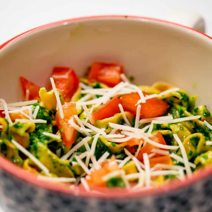 Basil spinach pesto pasta served with tomatoes and parmesan cheese