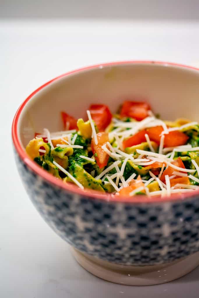 Basil spinach pesto pasta served with tomatoes and parmesan cheese