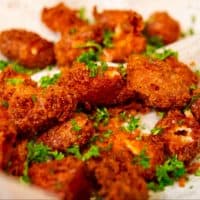 Deep fried cheese curds garnish with fresh parsley on a paper towel