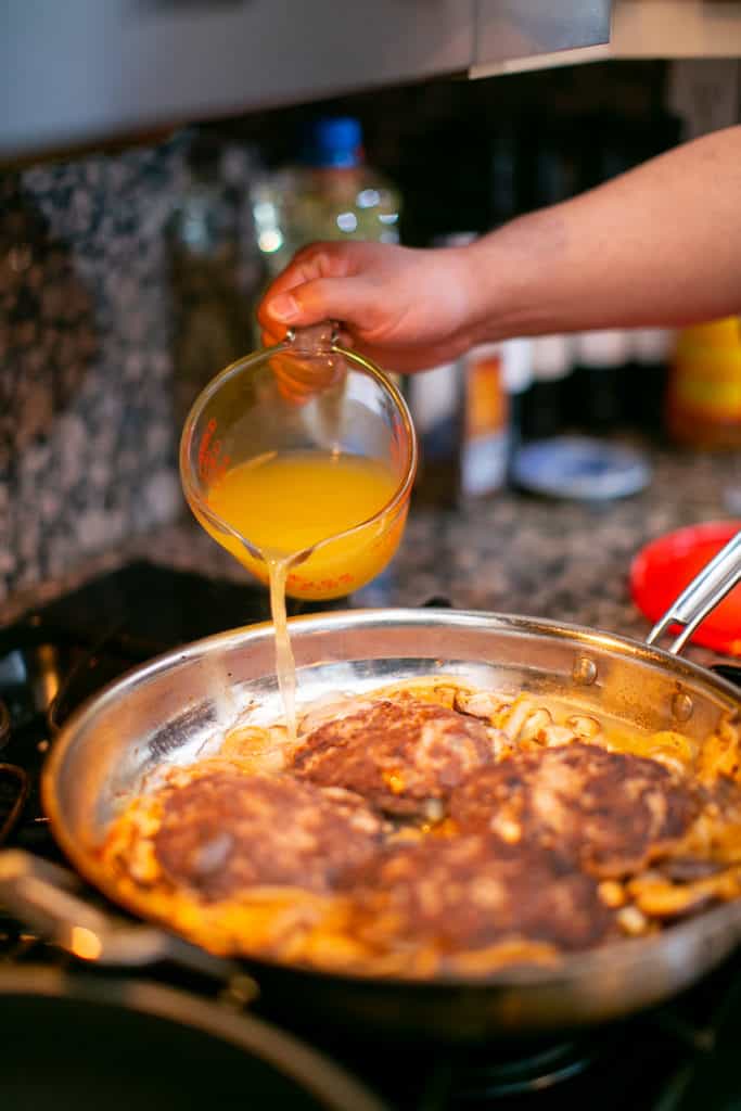 Pouring chicken stock over the chopped steak