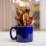 Baked crispy eggplant chips served on a blue ceramic mug placed on a white surface
