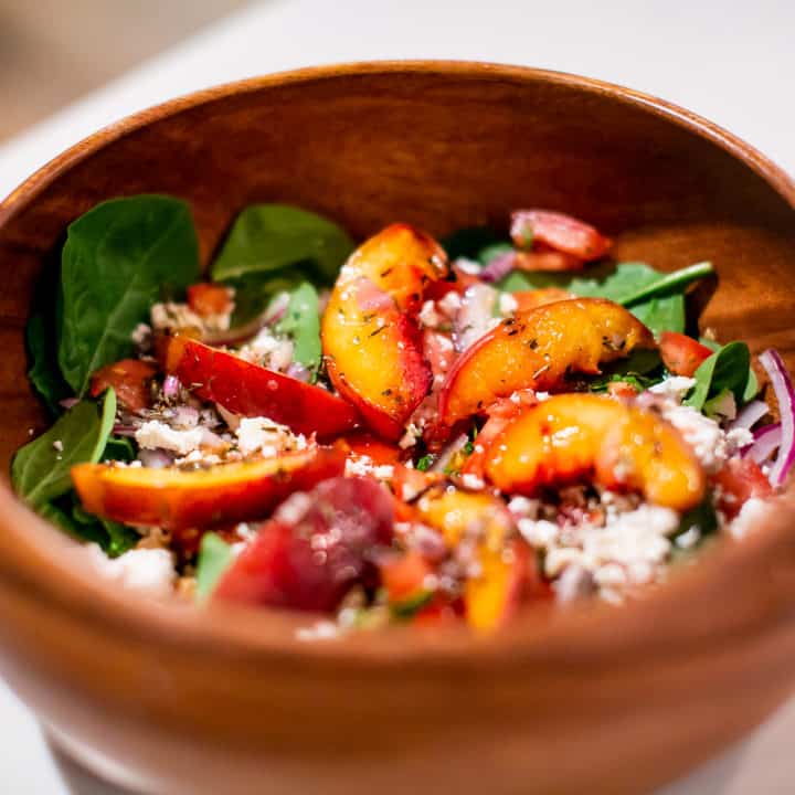 Grilled peach salad served on a wooden bowl