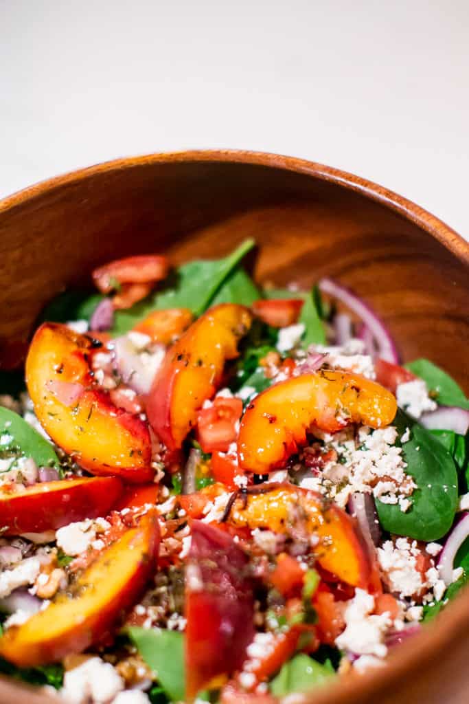 Close up of grilled peach salad on a wooden bowl