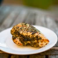 Lemon herb chicken served on a white plate placed on a brown wooden table