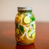 A closed jar full of spicy pickle juice placed on a brown wooden table