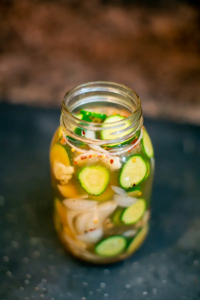 Homemade spicy pickle juice in a clear mason jar on a kitchen countertop