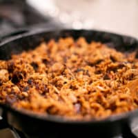 Pork carnitas cooked in black cast iron on a stove in the kitchen
