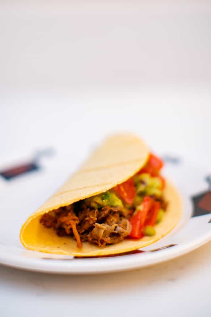 Close photo of pork carnitas enveloped in a taco shell