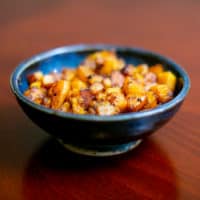 Roasted butternut squash served in a small blue ceramic bowl placed on a brown wooden table