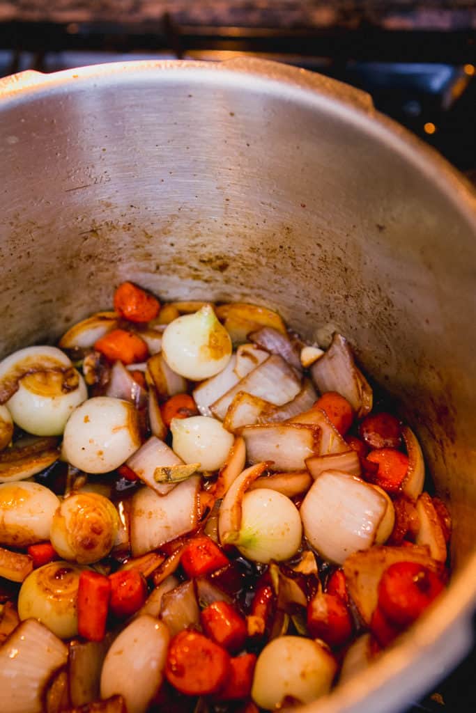 Carrots and onions cooking in a pressure cooker for Beef Bourguignon