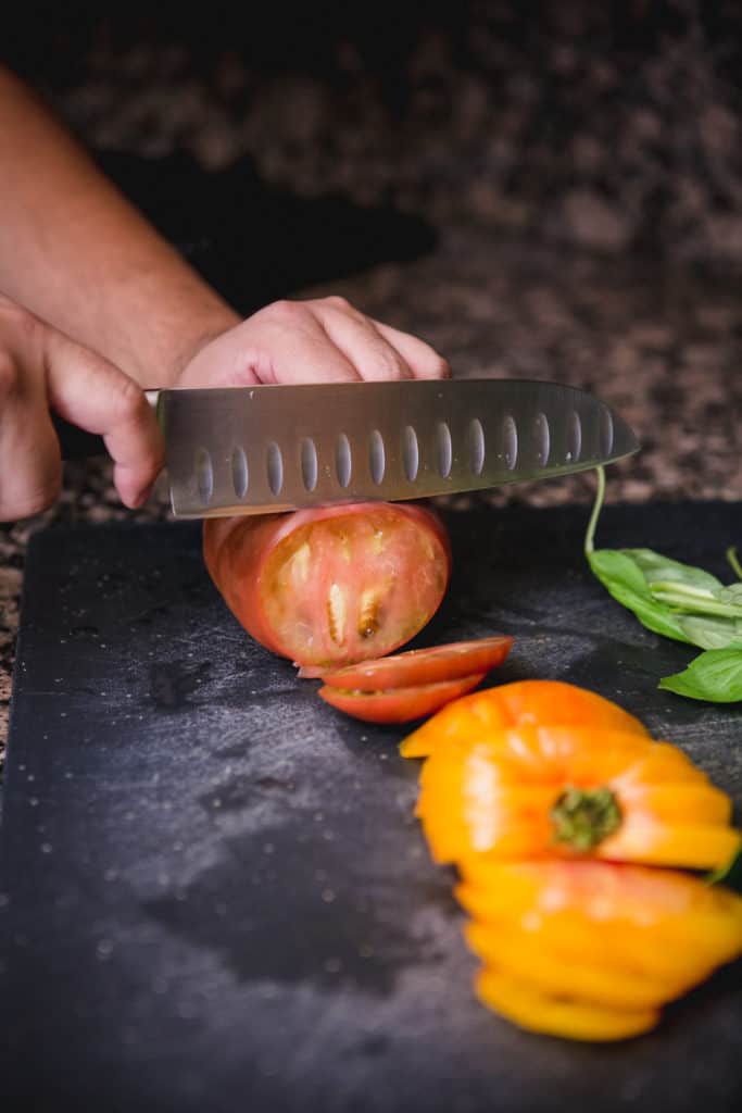 Slicing heirloom tomatoes with a chef's knife for a caprese salad