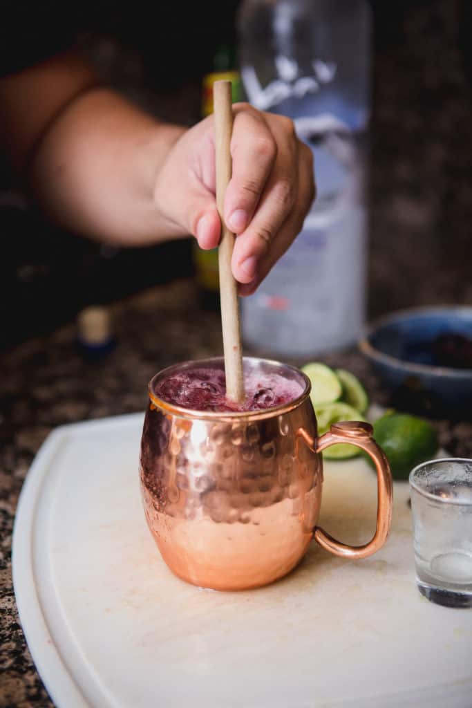 A man mixing a drink with a wooden muddler