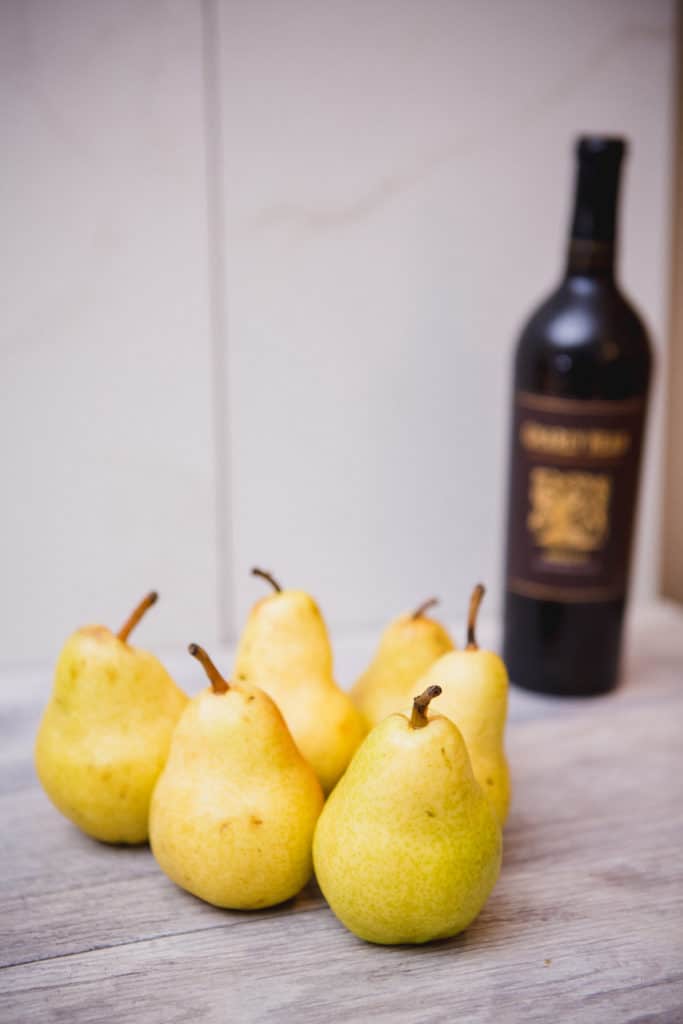 A bunch of pears in front of wine bottle