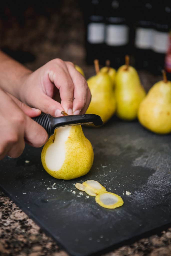 A man removing pear skin with a peeler