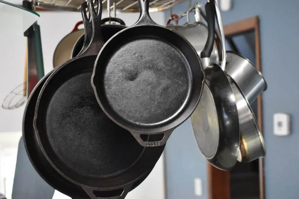 Cast iron pans and stainless steel pans hanging on a rail