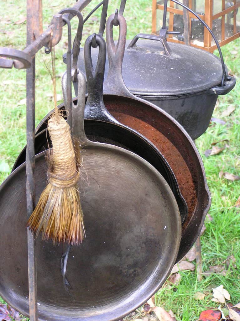 Different kinds of cast iron pans hanging on a rail