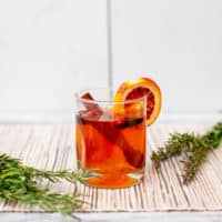 Mulled apple cider with rum in a clear glass placed on a brown placemat