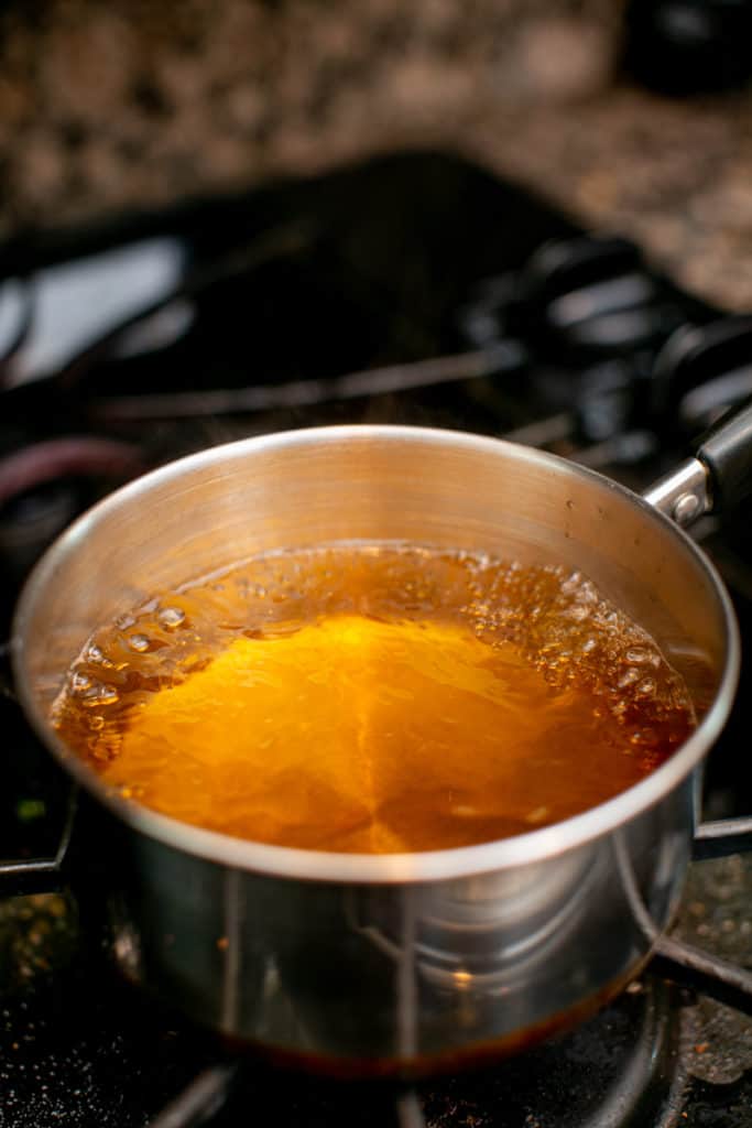 A mixture of apple cider and rum being cooked in a sauce pan 