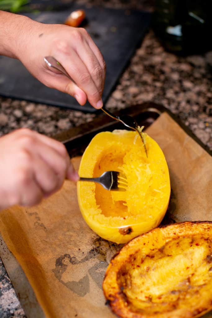 A man shredding a squash with two forks