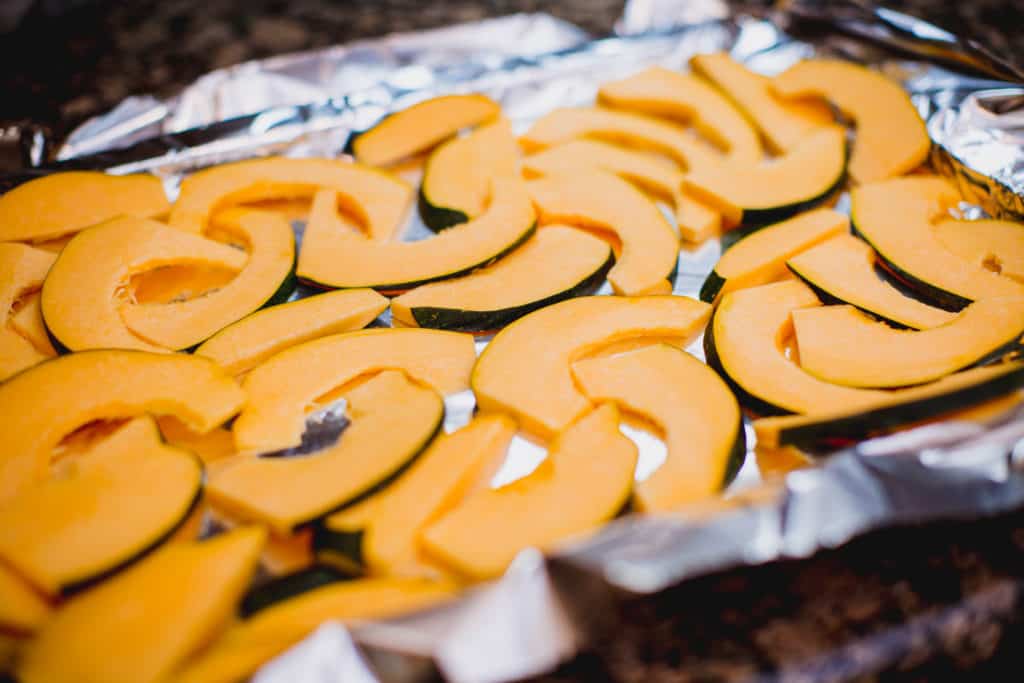 Acorn squash sliced and placed in a tray with foil