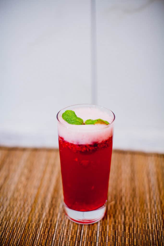A glass of cranberry champagne cocktail with raspberries