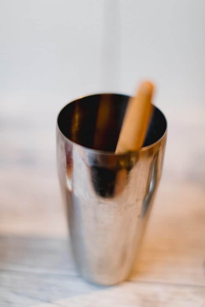 A shaker and a muddler for a cranberry bourbon smash cocktail