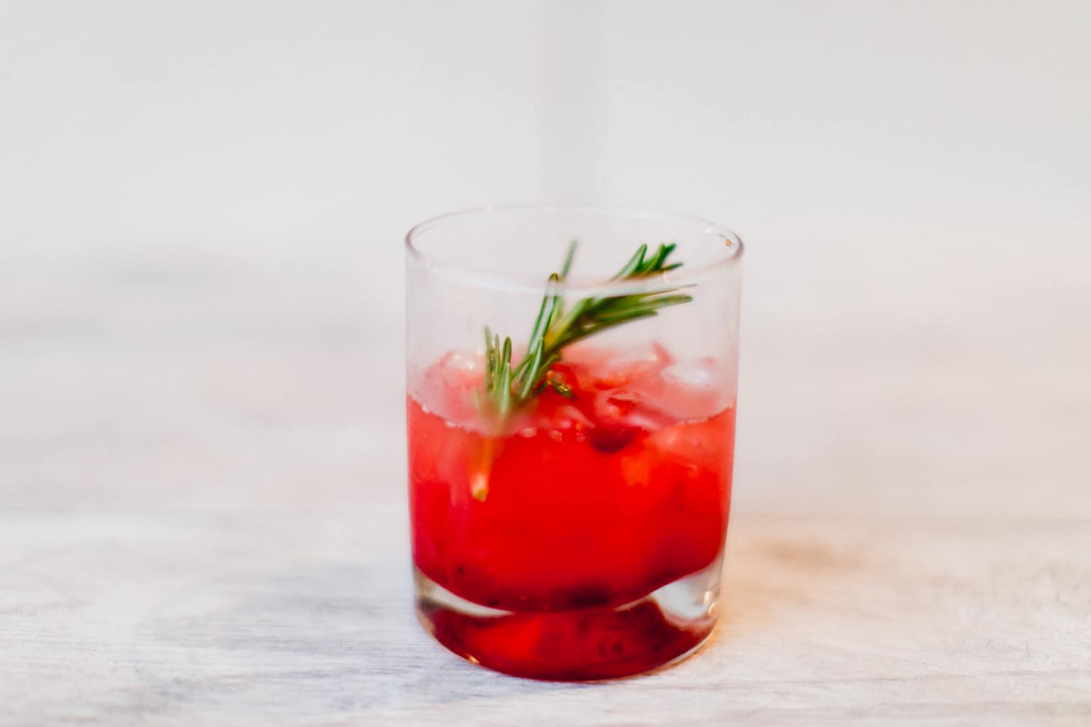 A cranberry bourbon smash cocktail topped with mint leaves