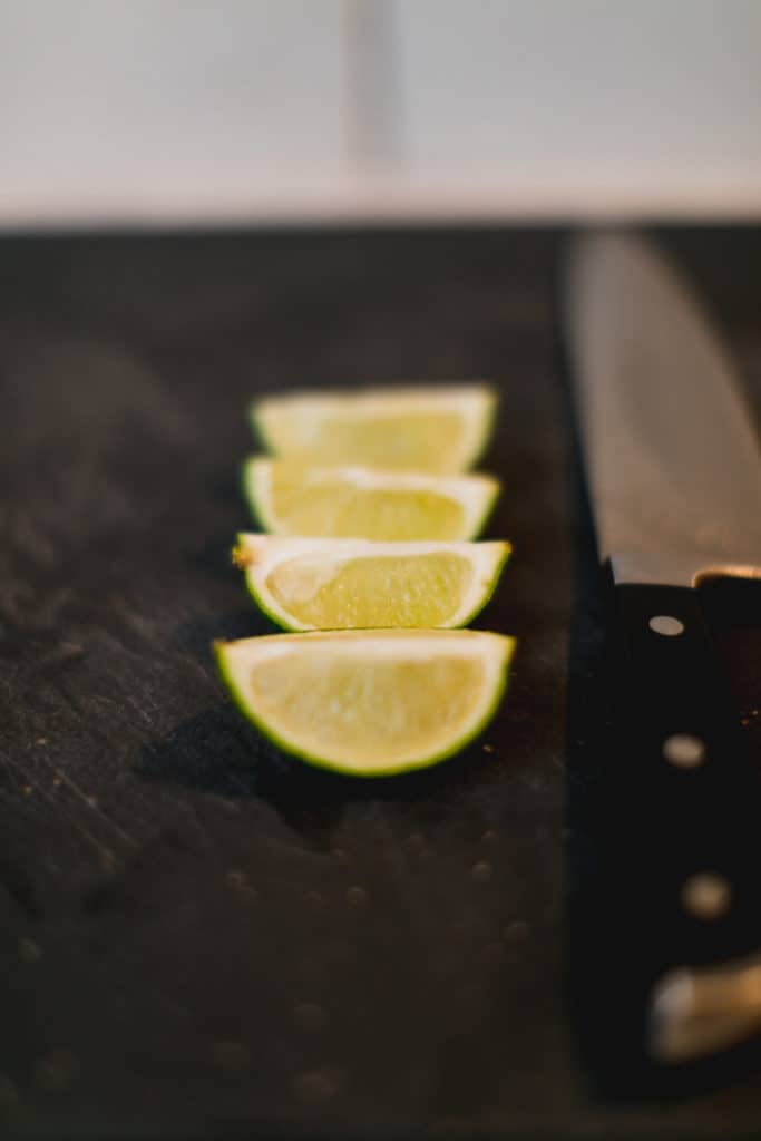 A row of lime wedges besides a knife