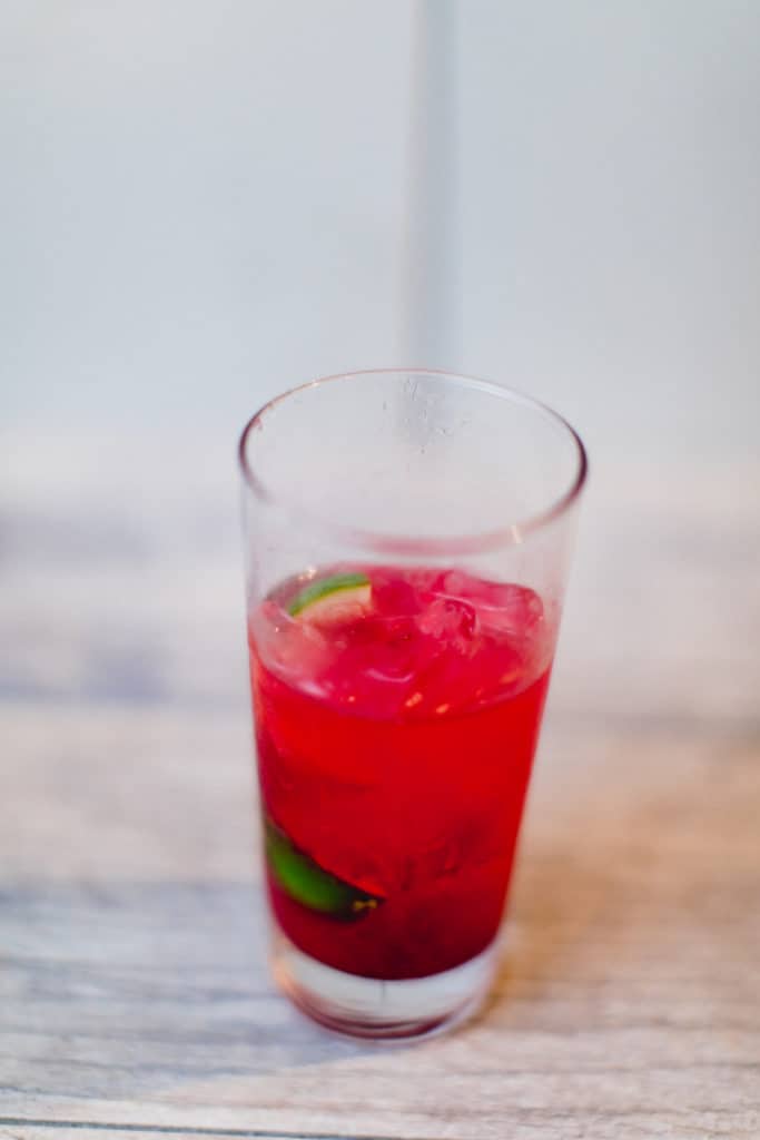 An ice-cold cranberry daiquiri served in a glass put on a wooden surface