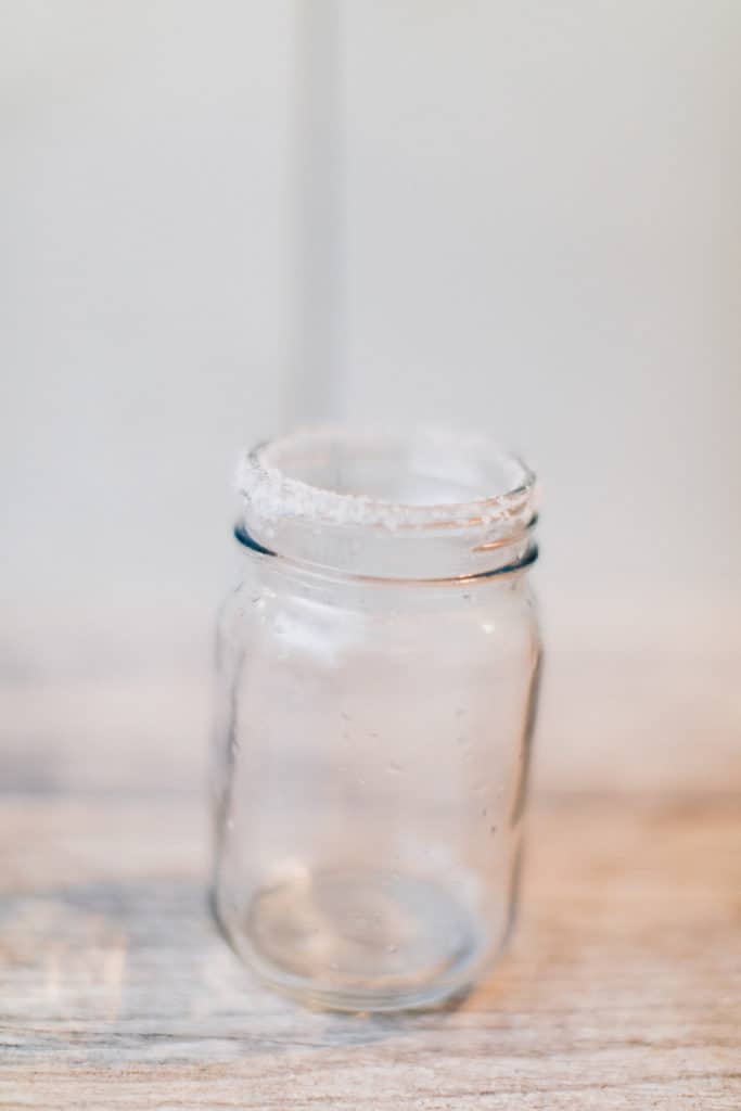 A glass rimmed with salt, prep for a cranberry margarita