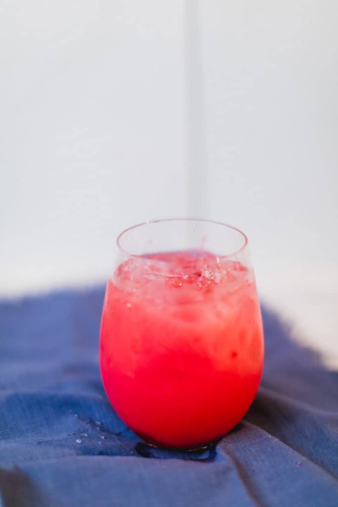 An ice-cold cranberry sea breeze cocktail served in a glass placed on a blue cloth