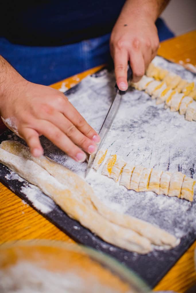 Person cutting logs of dough to make gnocchi