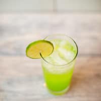 A top view of an ice-cold lime White Claw cocktail with a slice of lime put on a wooden surface