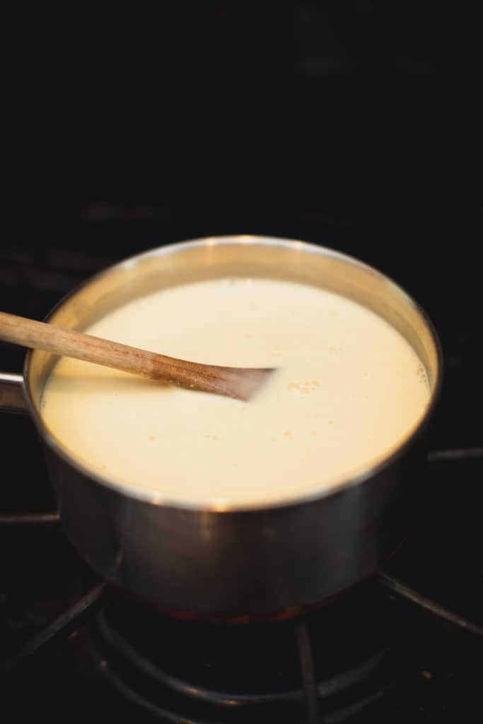 Ingredients for eggnog panna cotta recipe being mixed in a saucepan