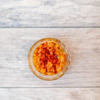 A top view of creamed corn is served in a small clear bowl placed on a wooden surface