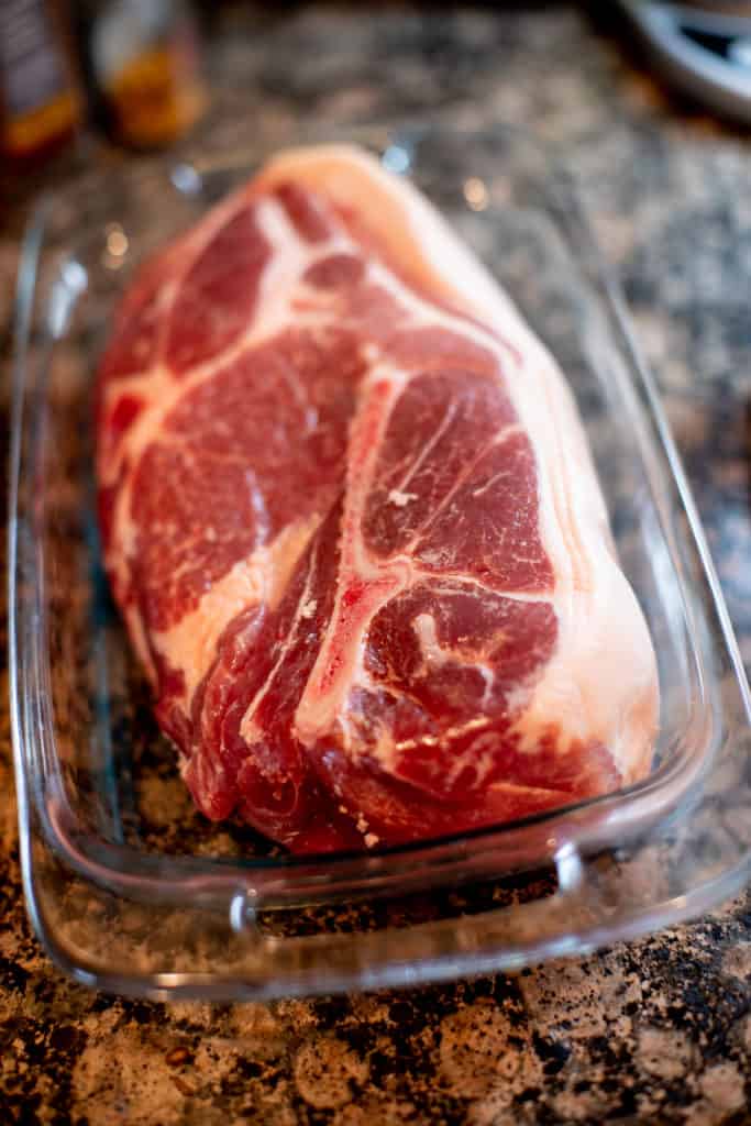 Pork shoulder in a baking dish being prepared to be baked in an oven