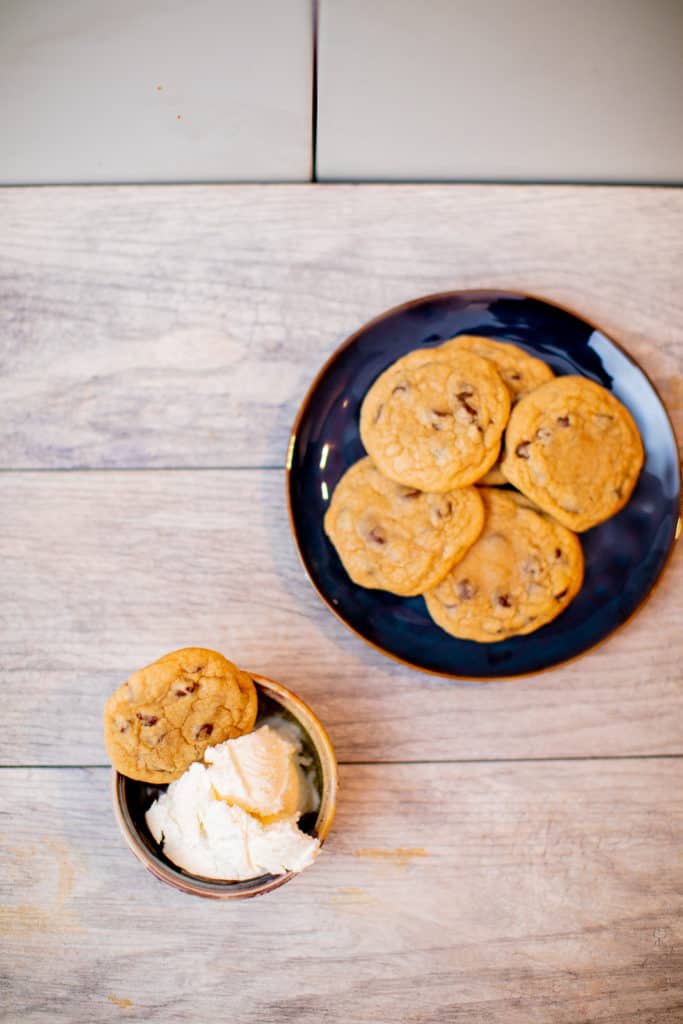 A plate full of homemade chewy chocolate chip cookies with a bowl of vanilla ice cream