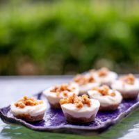 A no bake cheesecake bites are served on a purple tray placed on a glass table