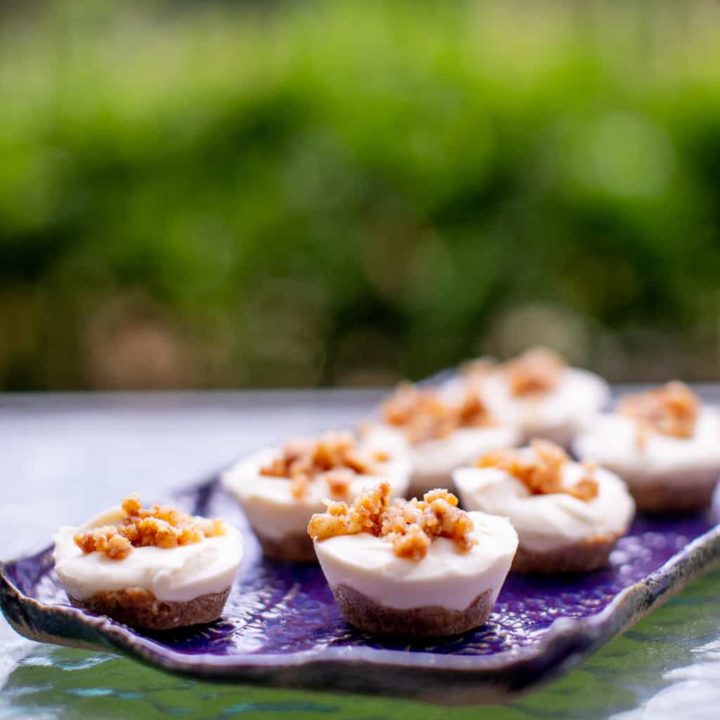 A no bake cheesecake bites are served on a purple tray placed on a glass table