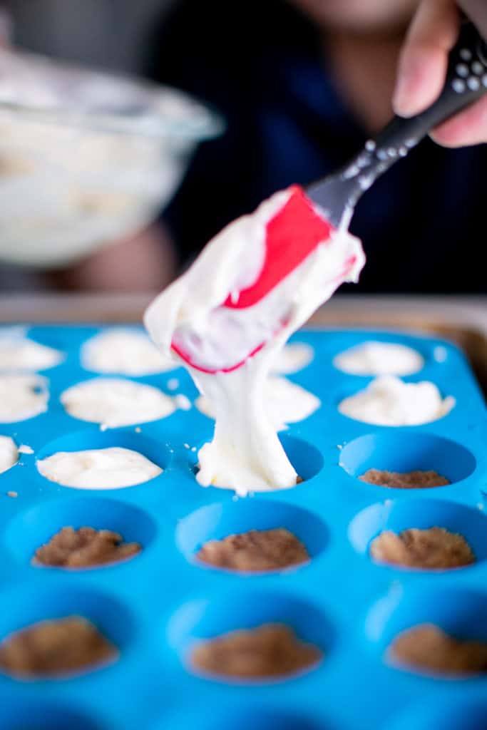 Person placing the cream cheese topping on the crusts