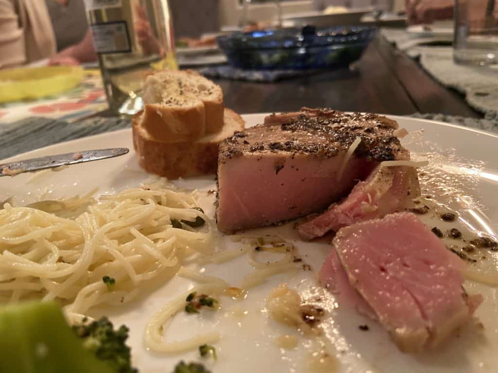 Peppered seared ahi recipe with pasta and garlic bread on a plate