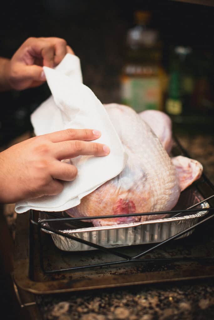 Man cooking and drying off a turkey with paper towels